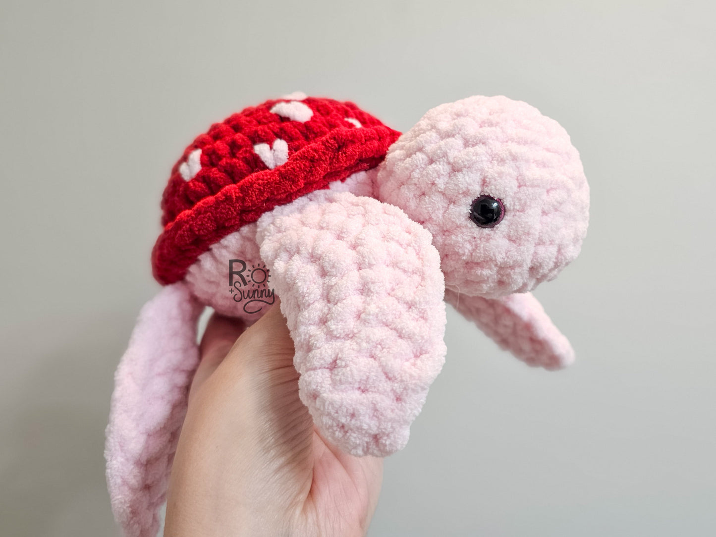 Sea of Love, Side Profile - Crochet sea turtle with a light pink body and red shell with white hearts.
