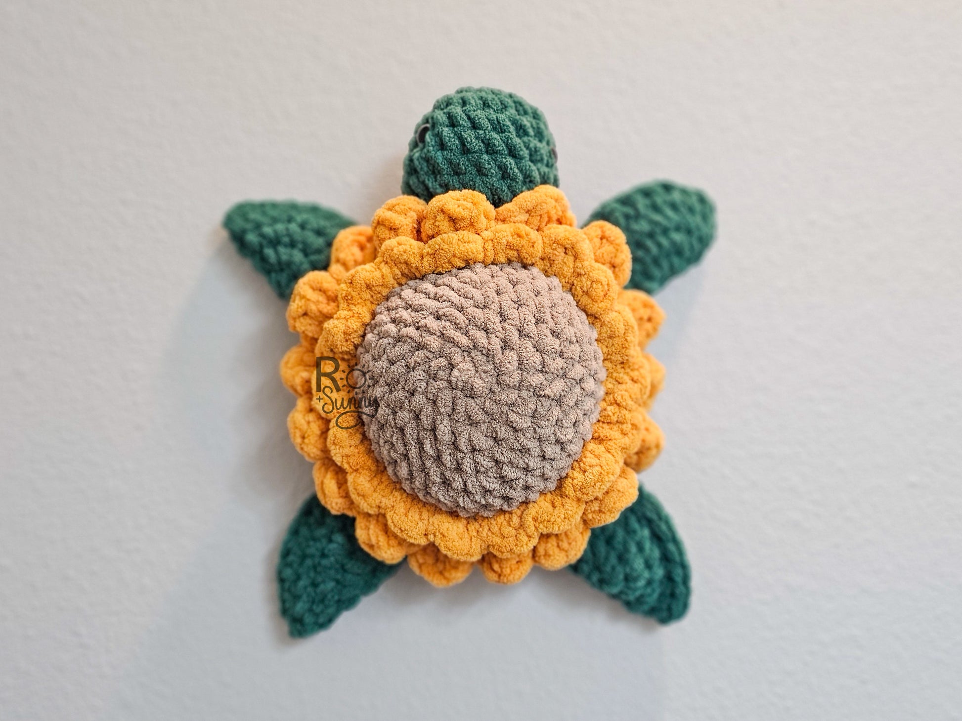 Sunflower, Overhead View, Lying Flat - Crochet sea turtle with a forest green body and golden yellow sunflower shell. The center of the sunflower is sandy brown. 