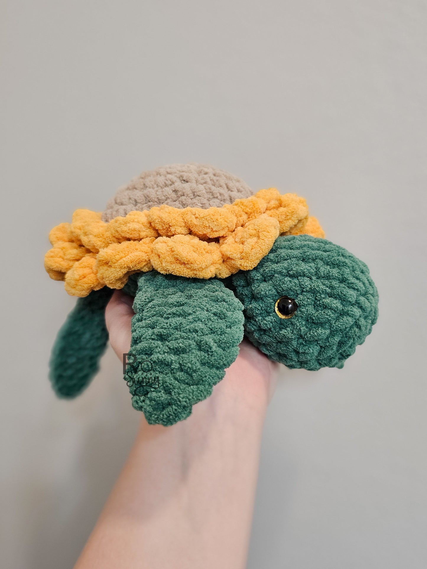 Sunflower, Side Profile View - Crochet sea turtle with a forest green body and golden yellow sunflower shell. The center of the sunflower is sandy brown. 