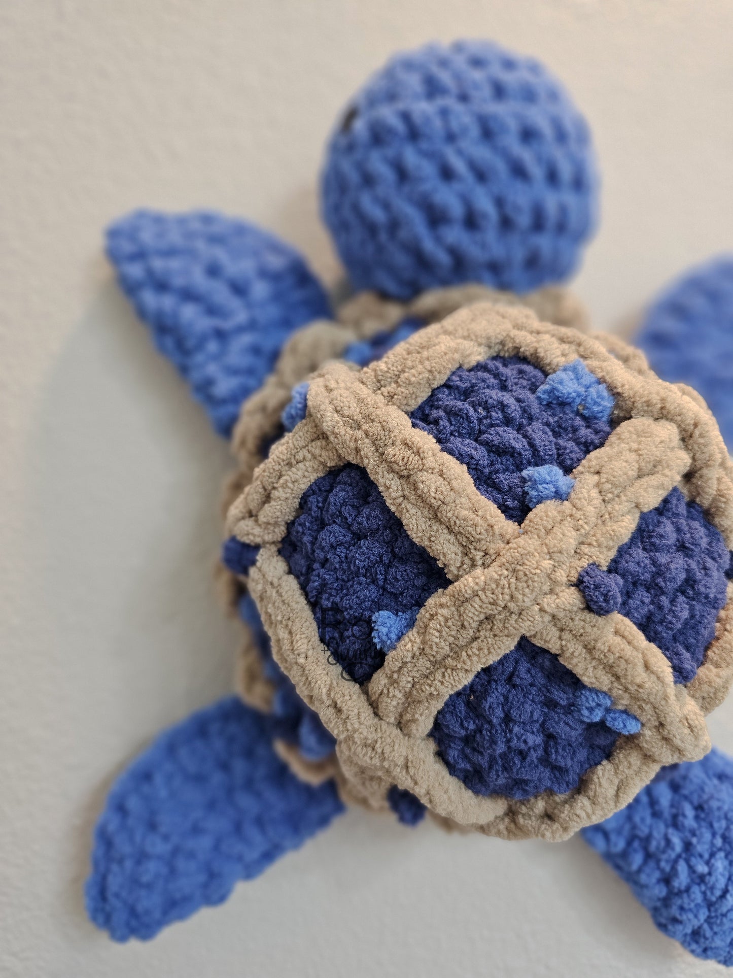 Blueberry Pie, Closeup - Crochet sea turtle with a blue body and shell that looks like a lattice crusted blueberry pie.  Little blueberries are embroidered on the pie shell to add texture. 