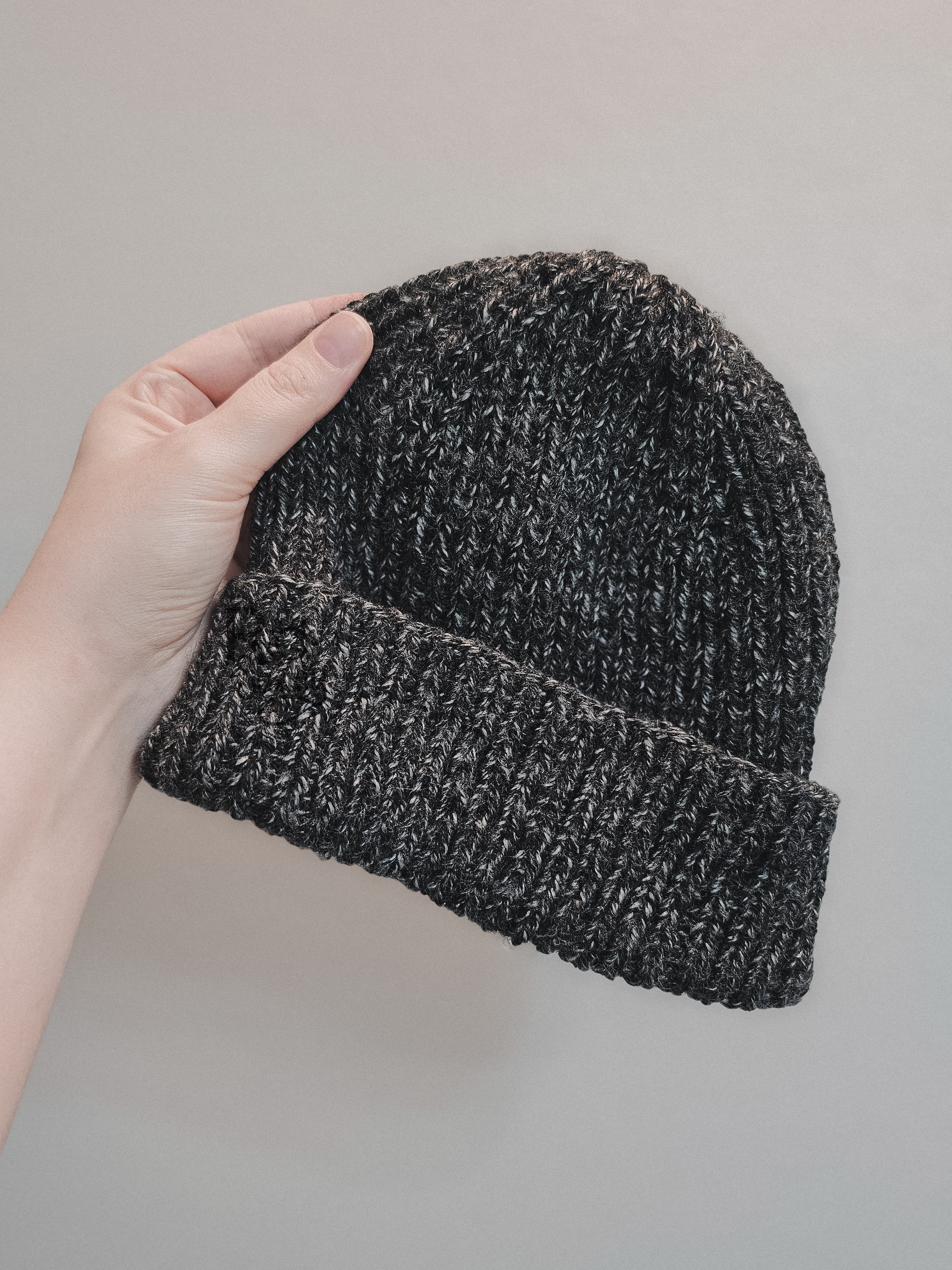 Hand holding knit had in a heathered charcoal gray yarn.