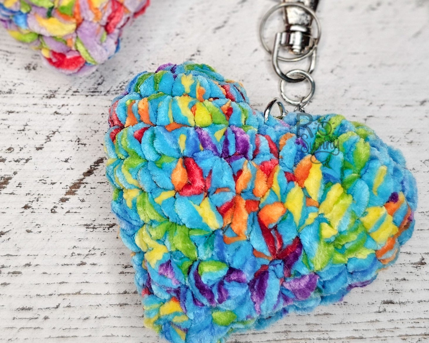 Crochet hearts in a rainbow of colors attached to keychains. 