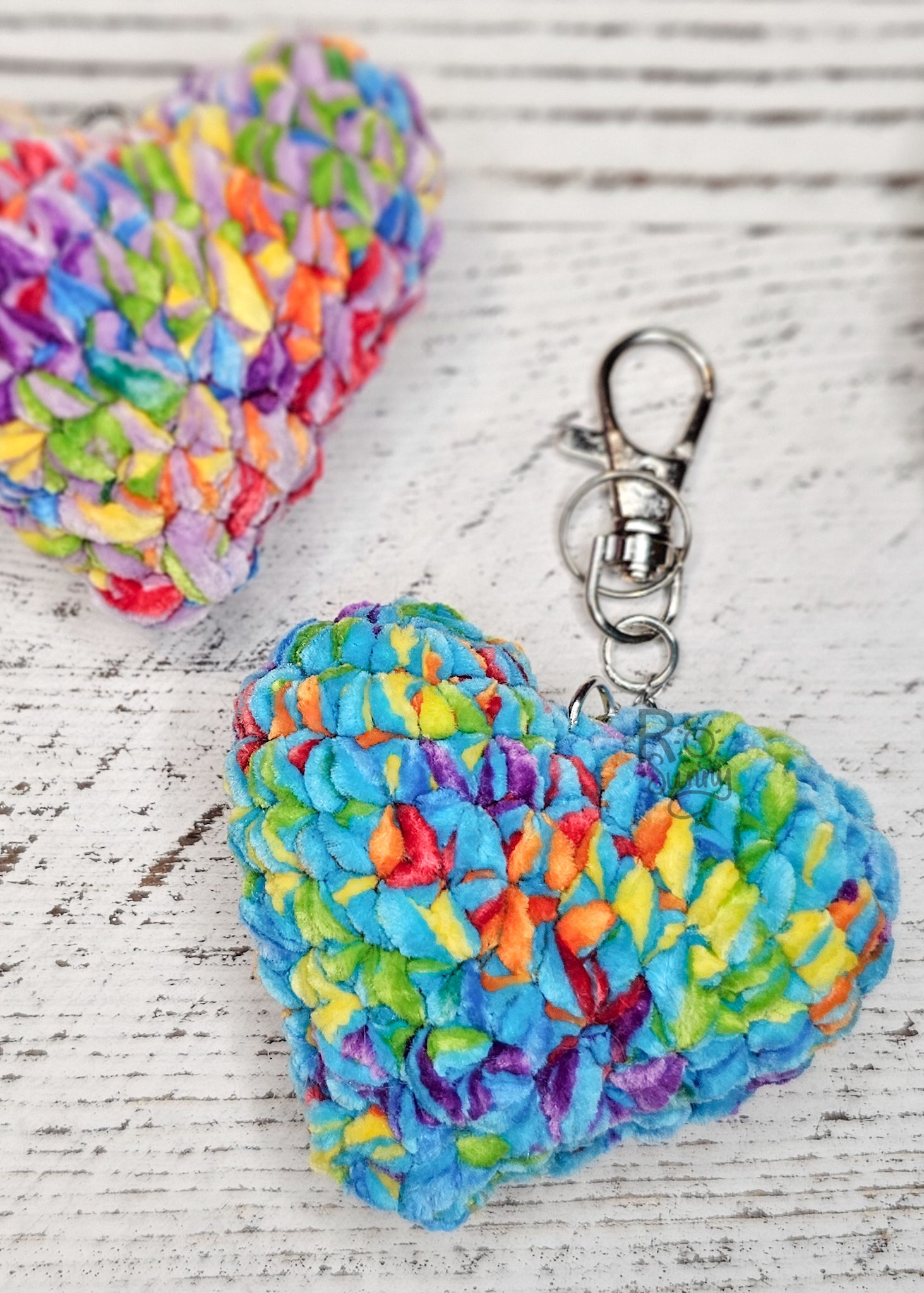 Crochet hearts in a rainbow of colors attached to keychains. 