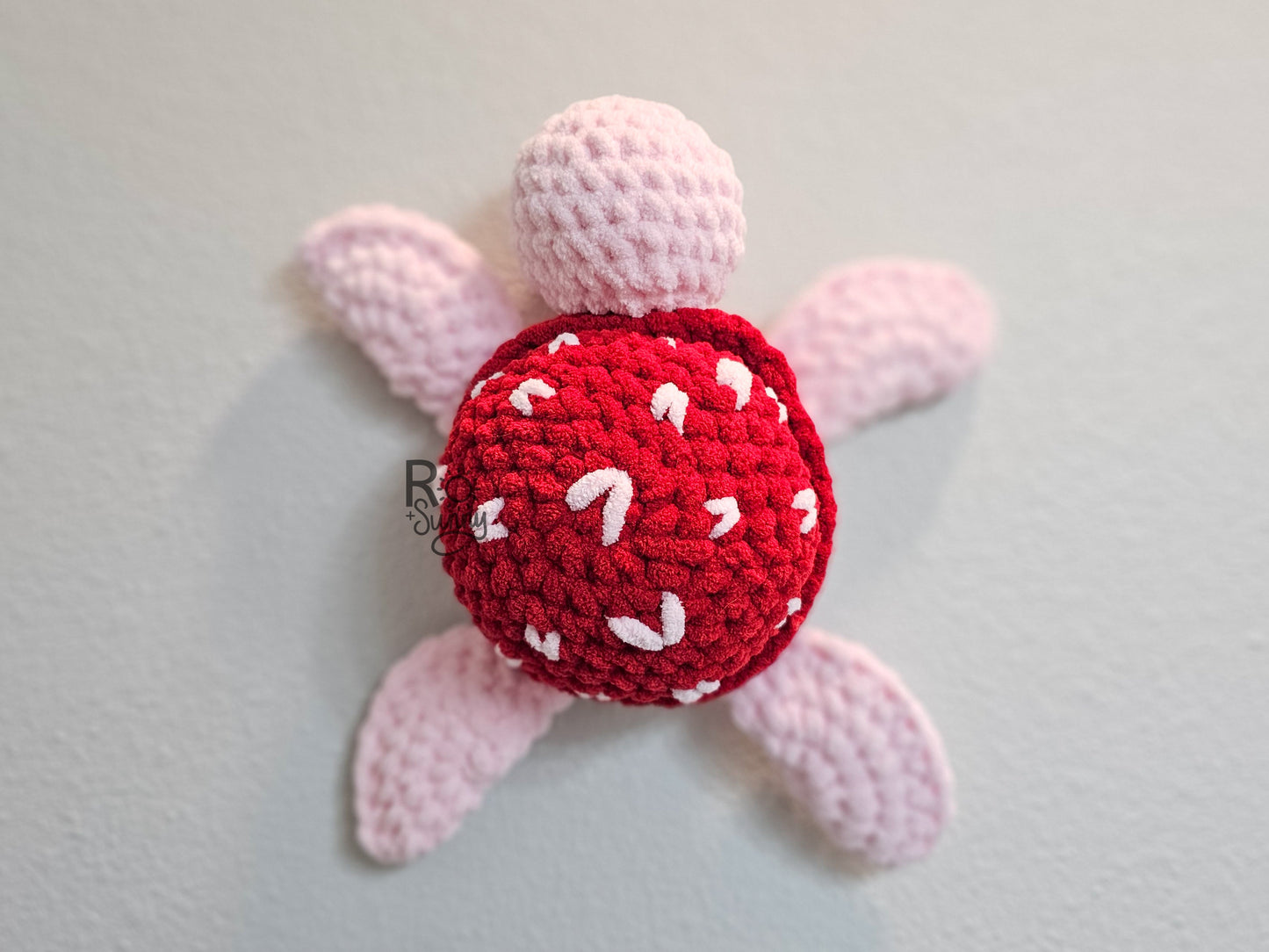 Sea of Love, Overhead, Lying Flat - Crochet sea turtle with a light pink body and red shell with white hearts.